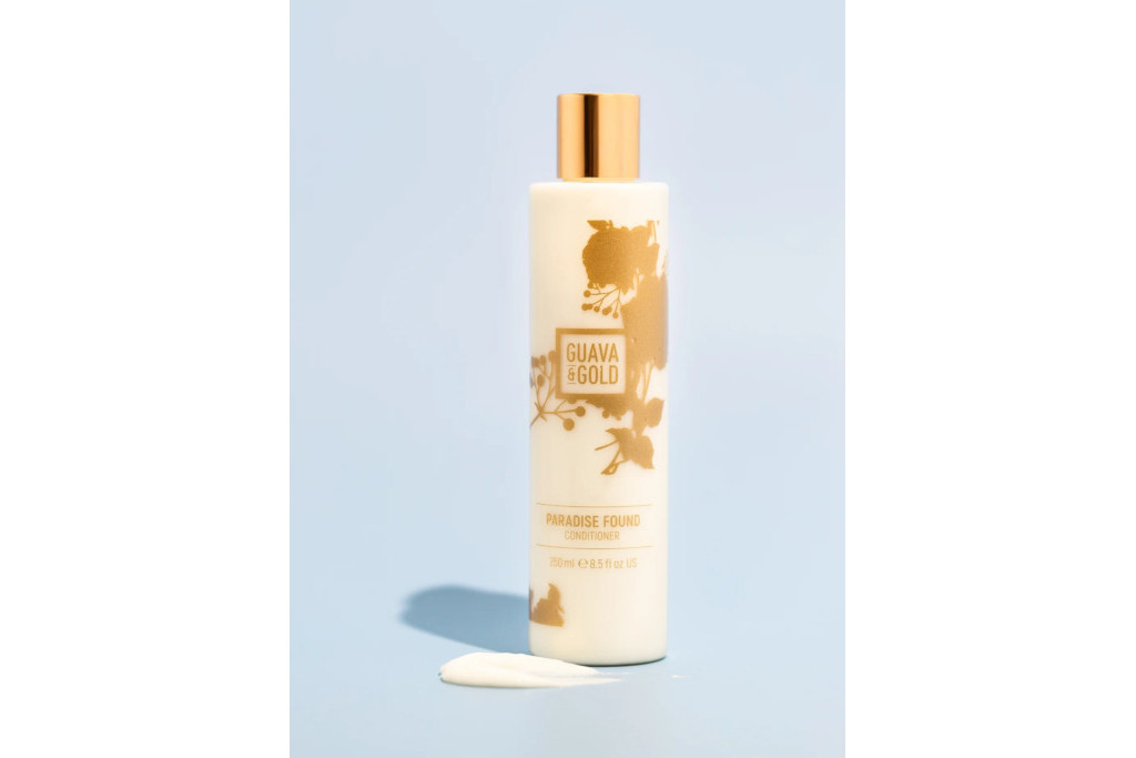 Cream bottle with gold detailing and cap on light blue background