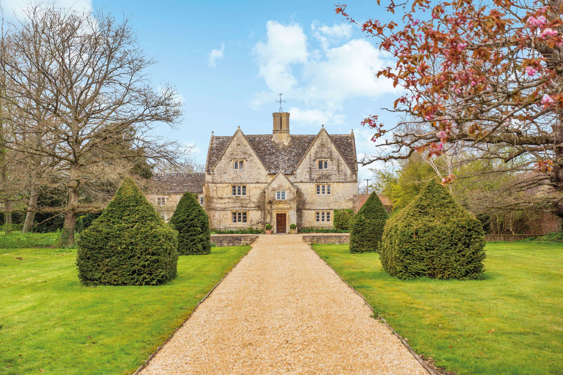 exterior shot of Jacobean manor house in Wiltshire with long drive and manicured gardens