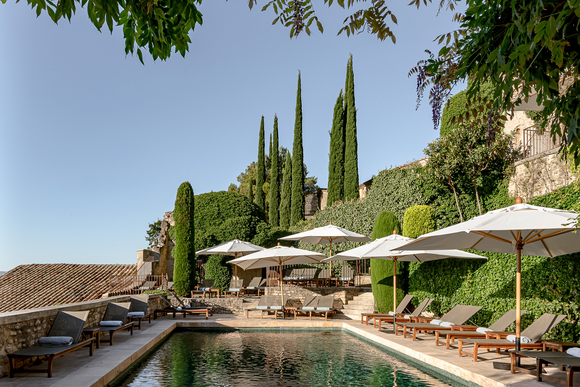 A small swimming pool surrounded by parasols and sunbeds