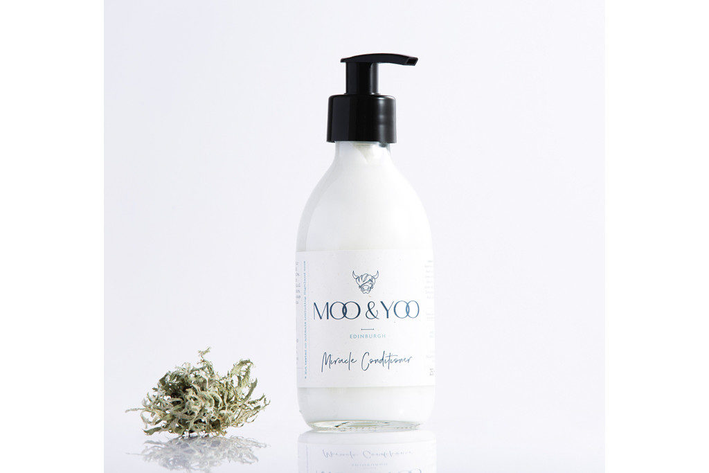White bottle with black pump next to pile of foliage
