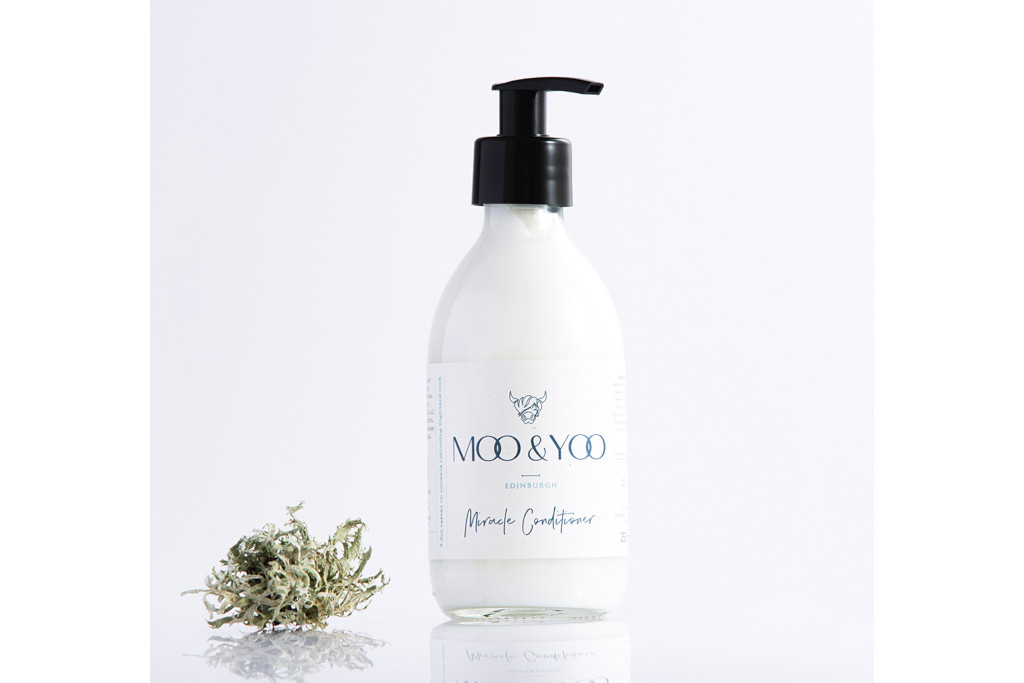 White bottle with black pump next to pile of foliage