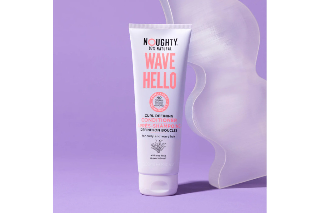 Purple bottel of conditioner with pink text, in front of purple background with clear wavy sculptural piece