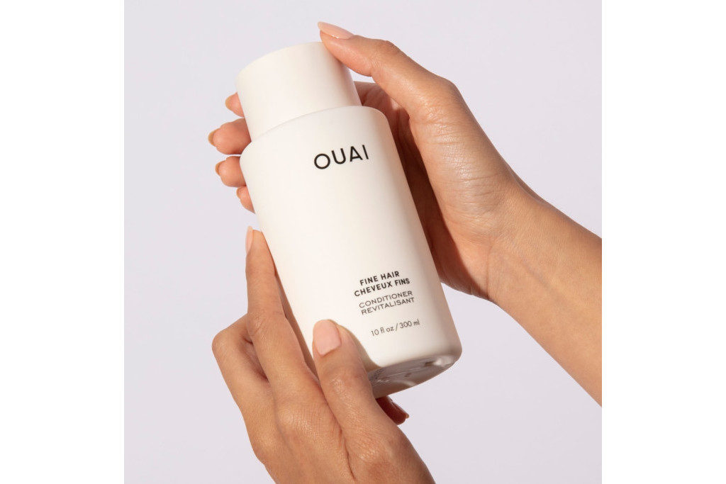 Hands holding white bottle on grey background