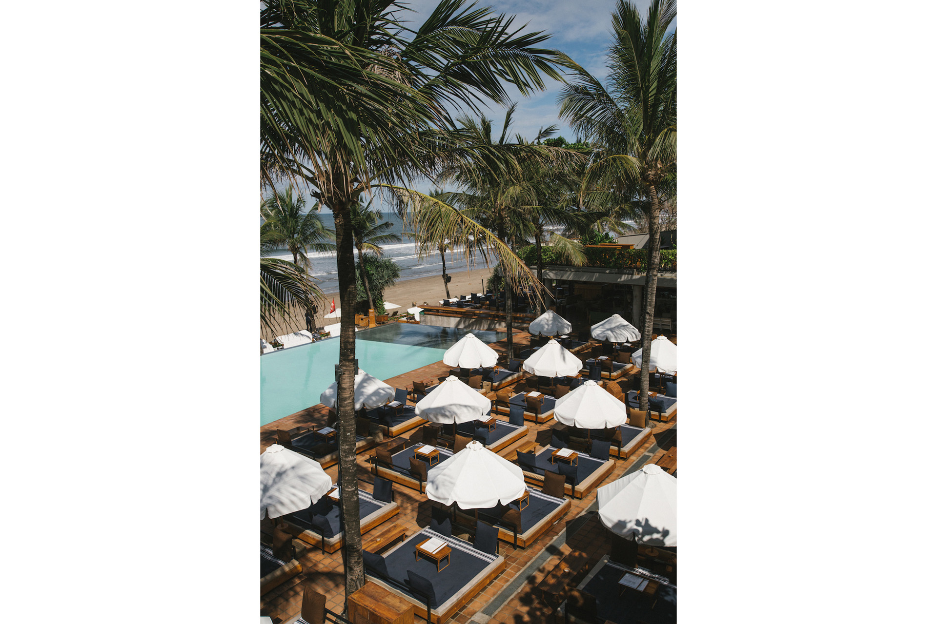 Parasols and palm trees by the pool at Potato Head Beach Club