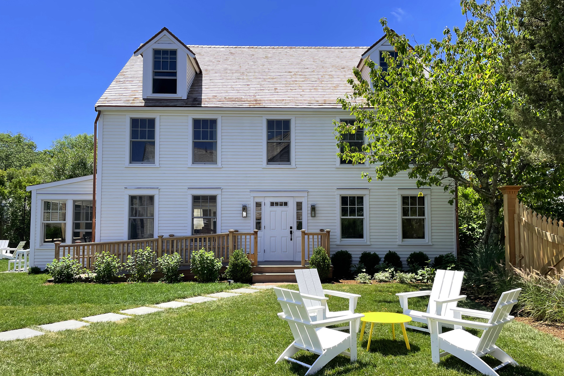 A white building against a blue sky with chairs on the grass in the foreground