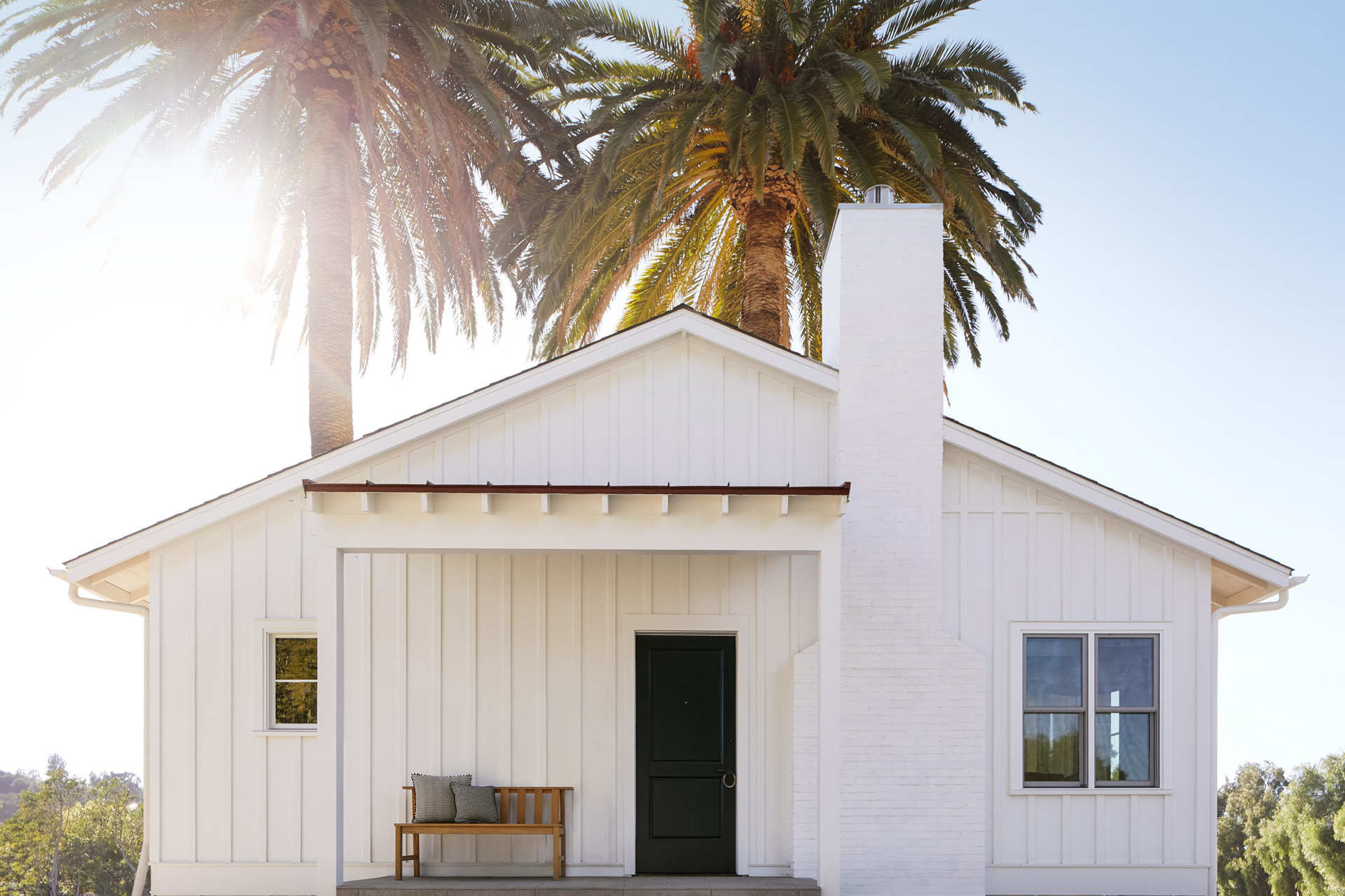 a white barn style house with palm trees behind