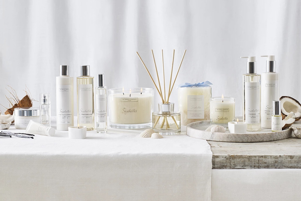Candles, diffusers and body wash lined up on white table