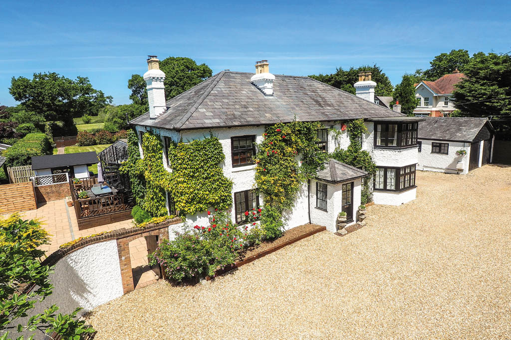 wisteria clad white property with stone driveway