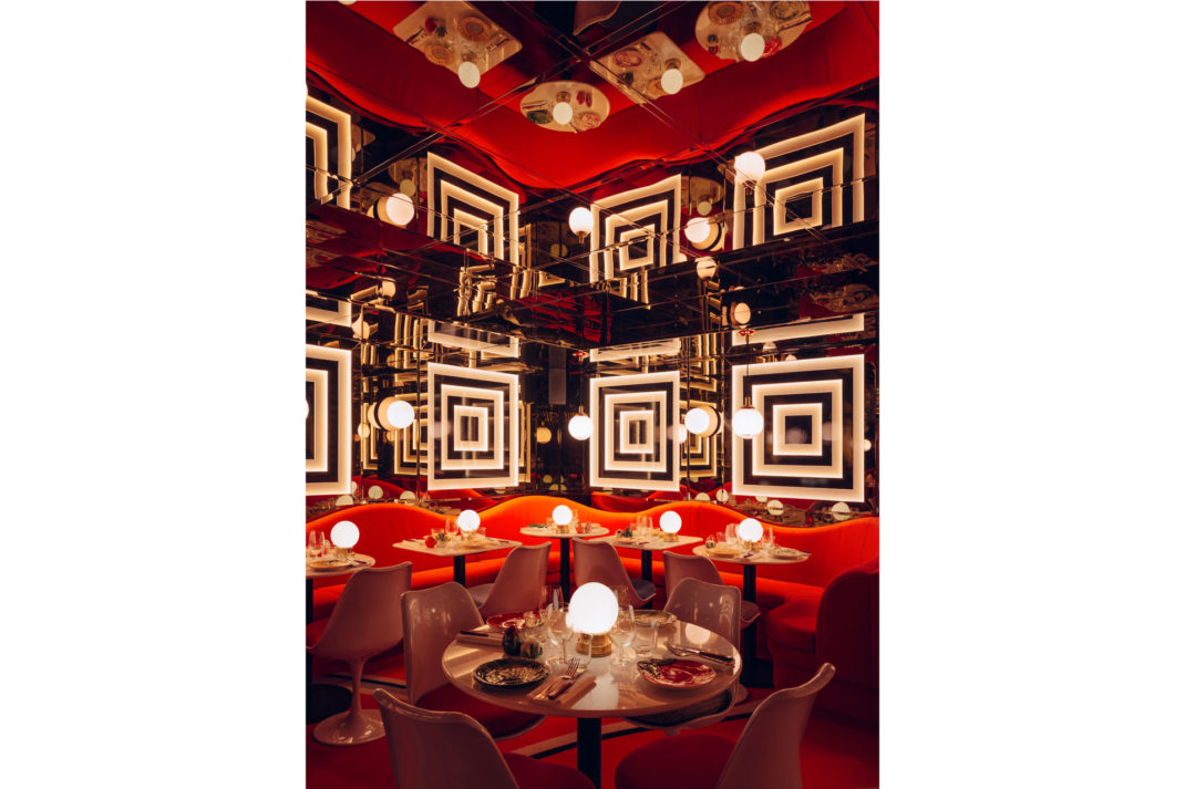 a close up shot of a table with pink chairs in a mirrored red room of the Ave Mario Restaurant in London