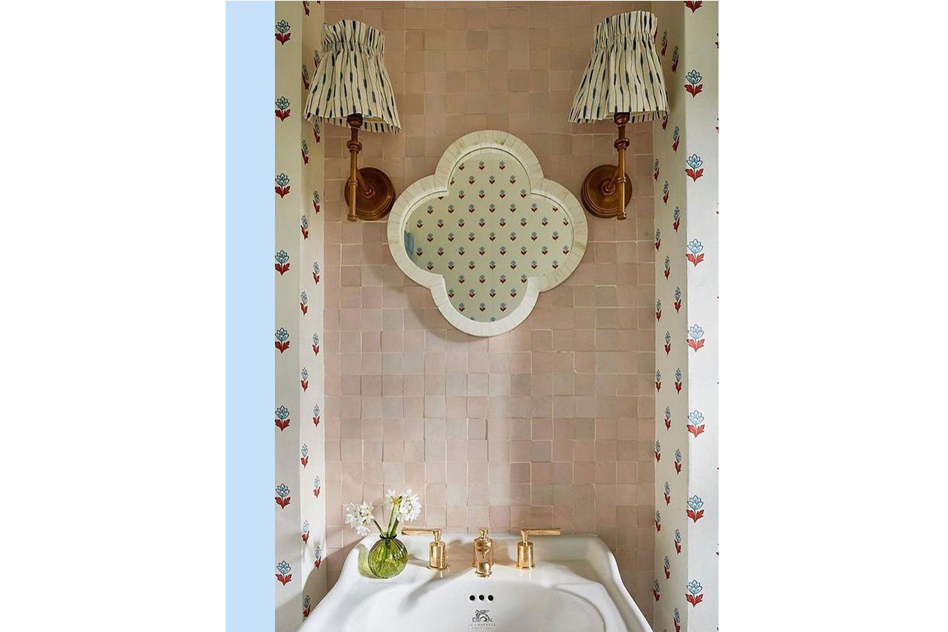 a quatrefoil mirror with pink tiling and white sink in a bathroom by Collagerie