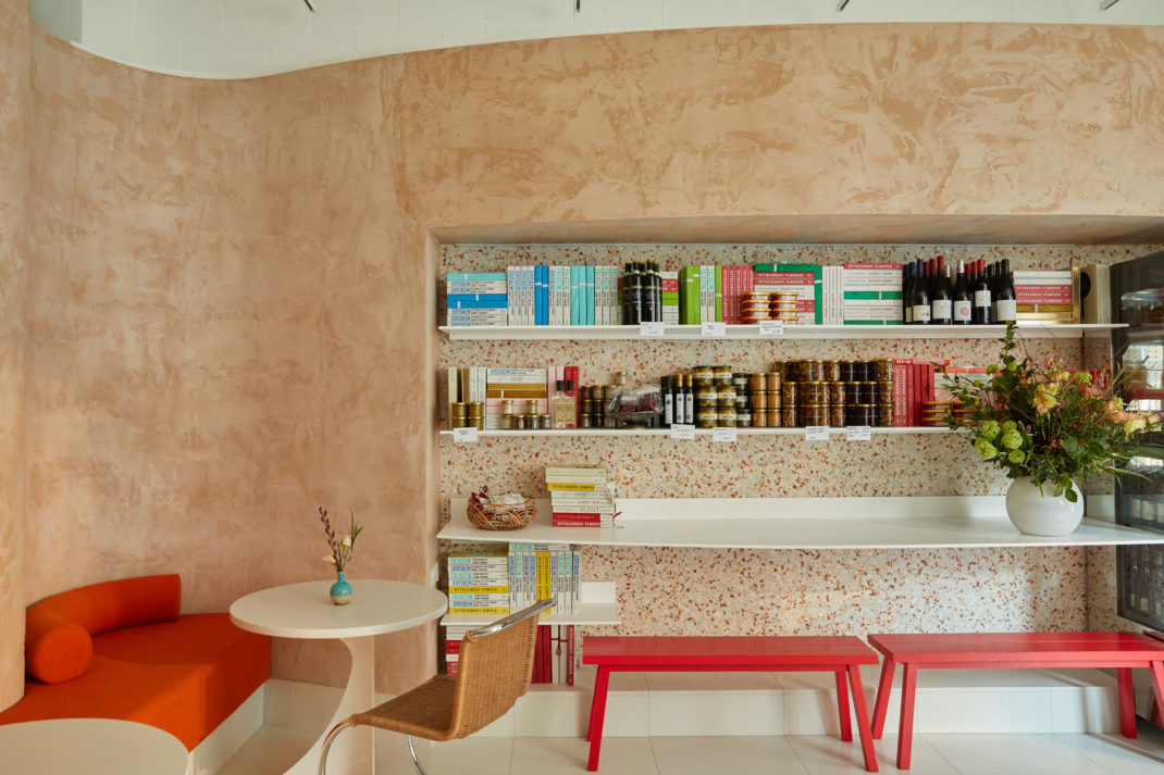 Ottolenghi Chelsea interior with a red sofa, pink walls, and a book shelf