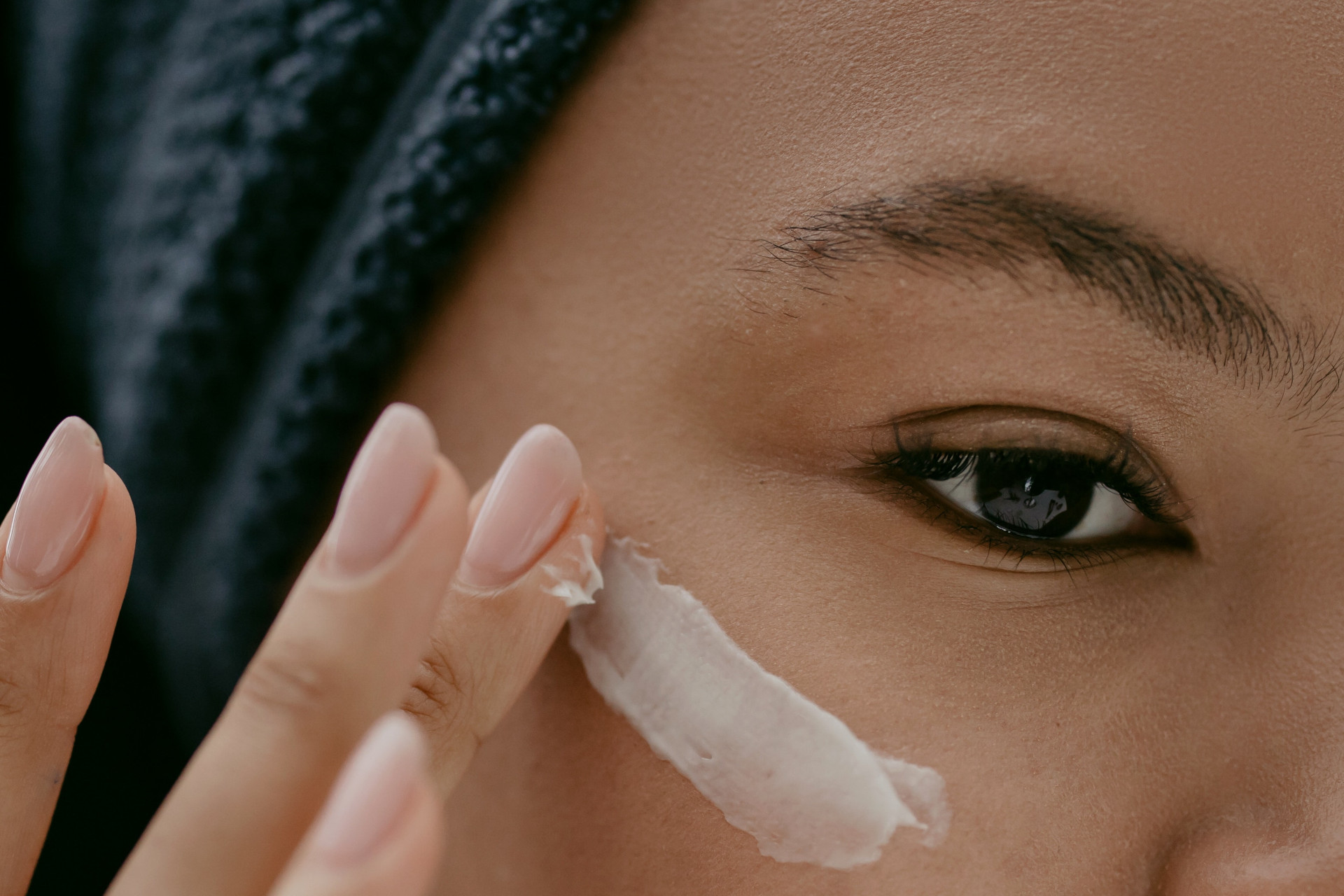 Close up of a mixed race woman applying cream under her eye