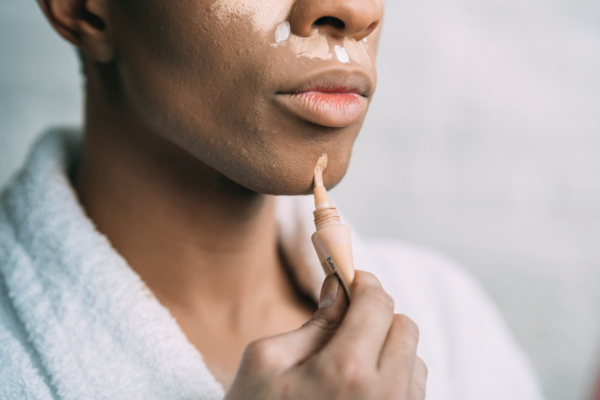 Close up of model applying skin-coloured cream to chin