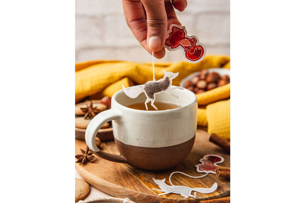 hand holding fox shaped teabag dangling it into mug