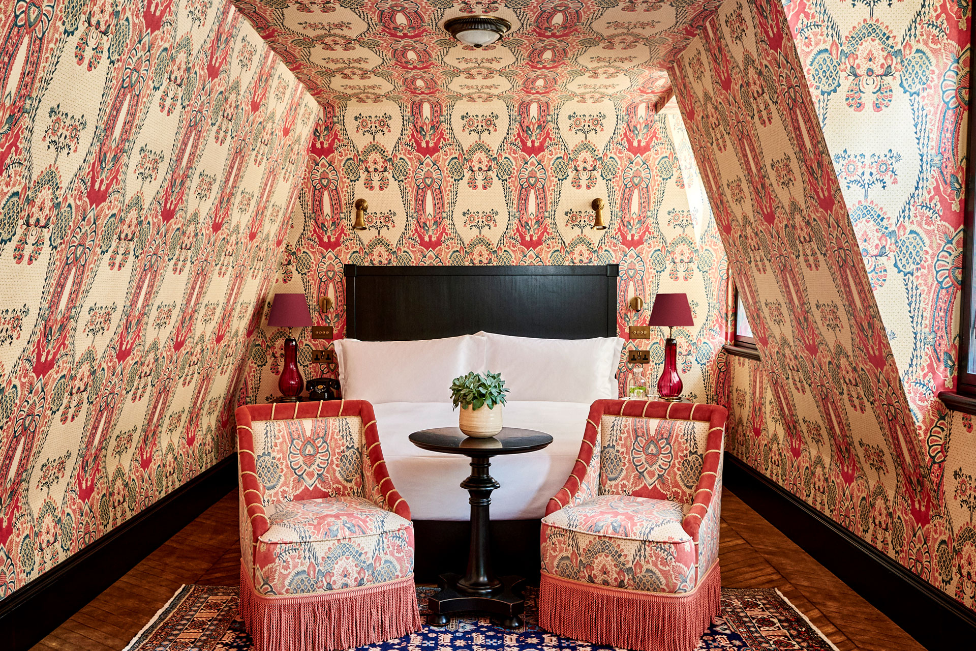 A maximalist Bedroom with patterned pink wallpaper and matching double chairs in the new hotel in Mayfair, Twenty Two