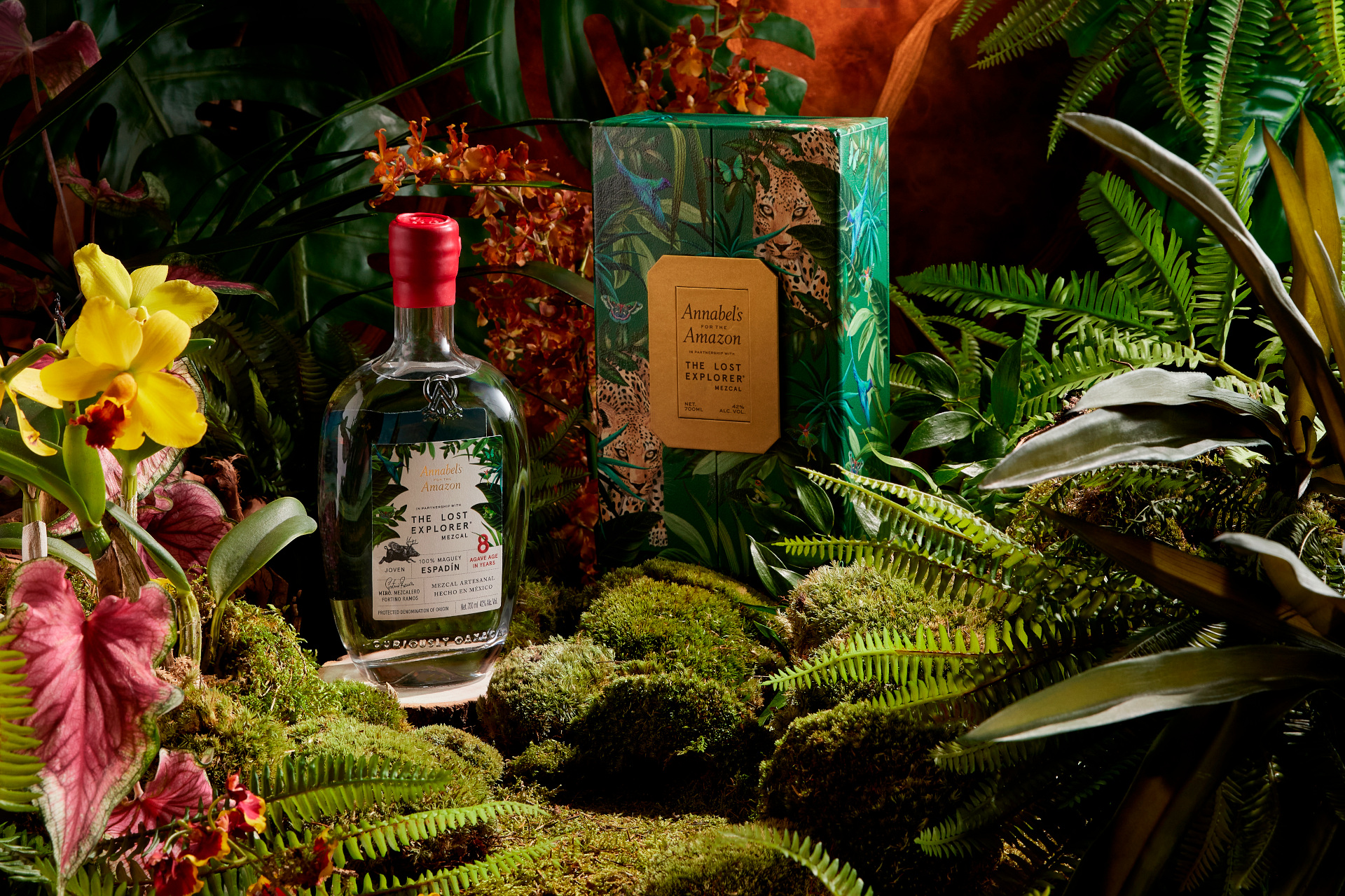 Leafy setting with moss and flowers, with a bottle and green box set in the middle