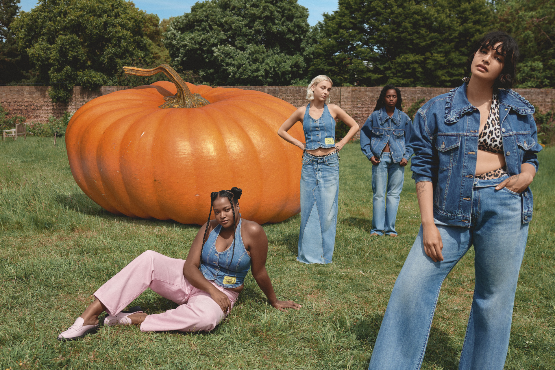 Models in denim outfits sat outdoors nect to giant pumpkin