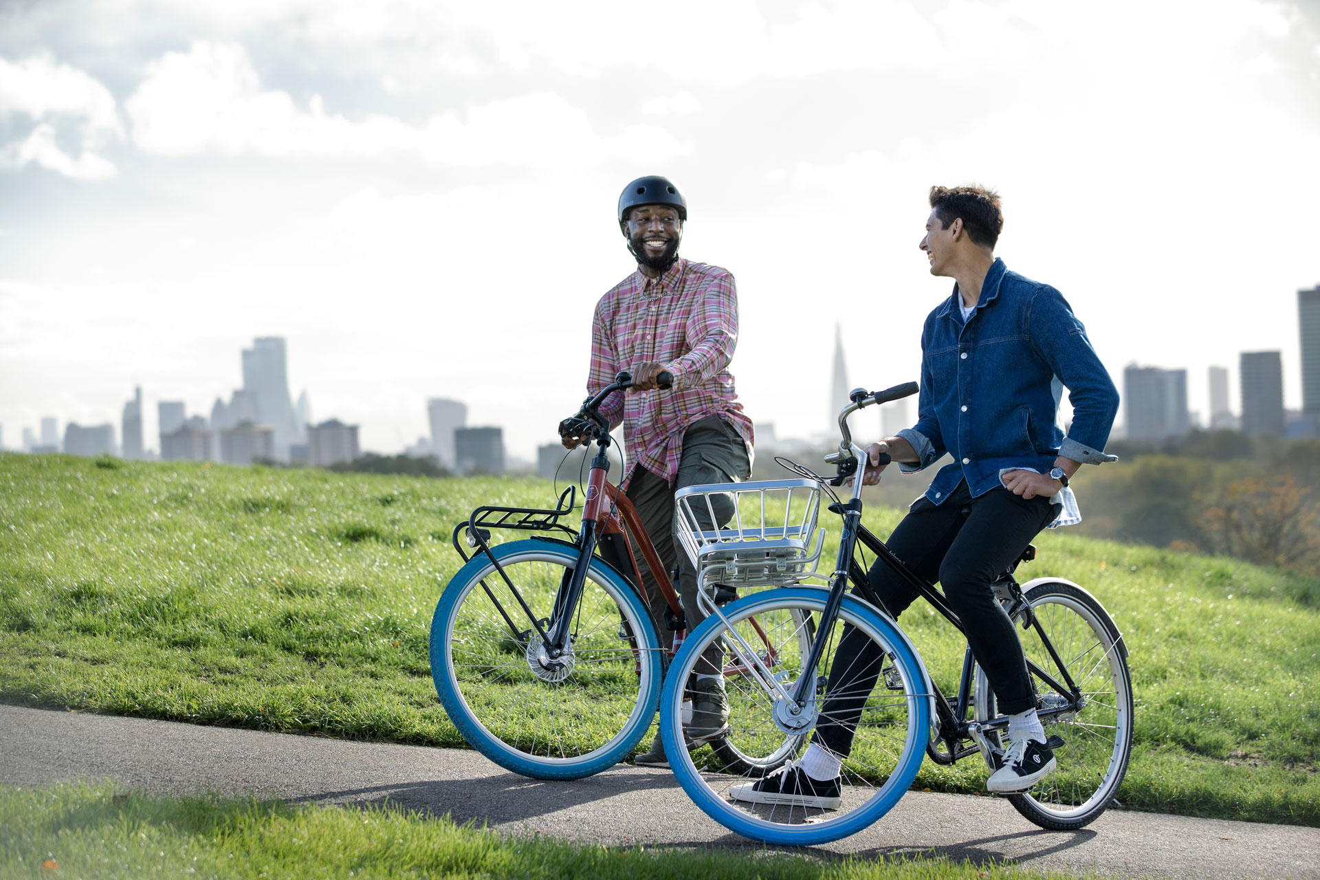 Two men on hill with e-bikes smiling