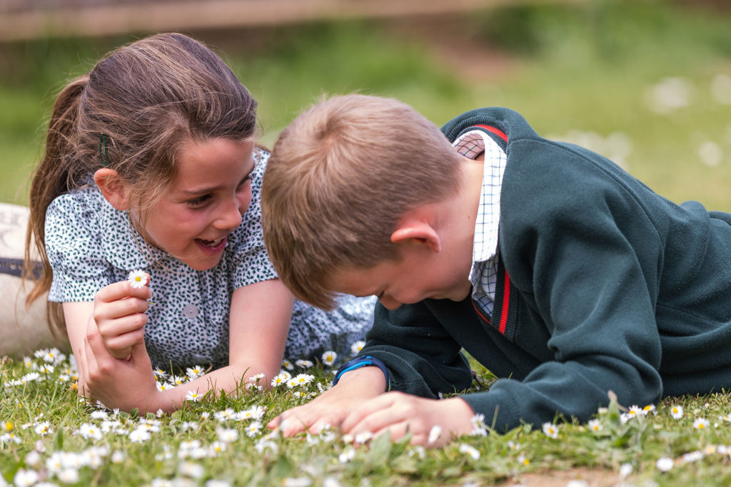 Two school children lying among daisies