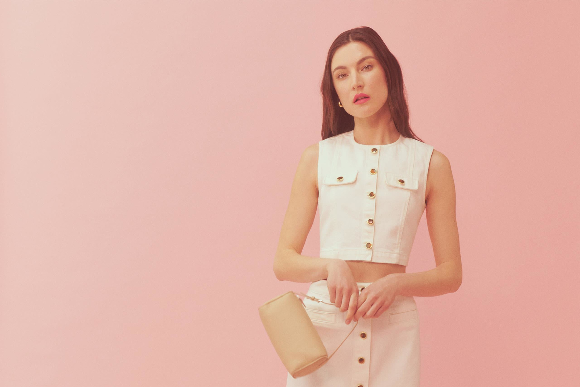 Model in white denim co-ord stood in front of pink background