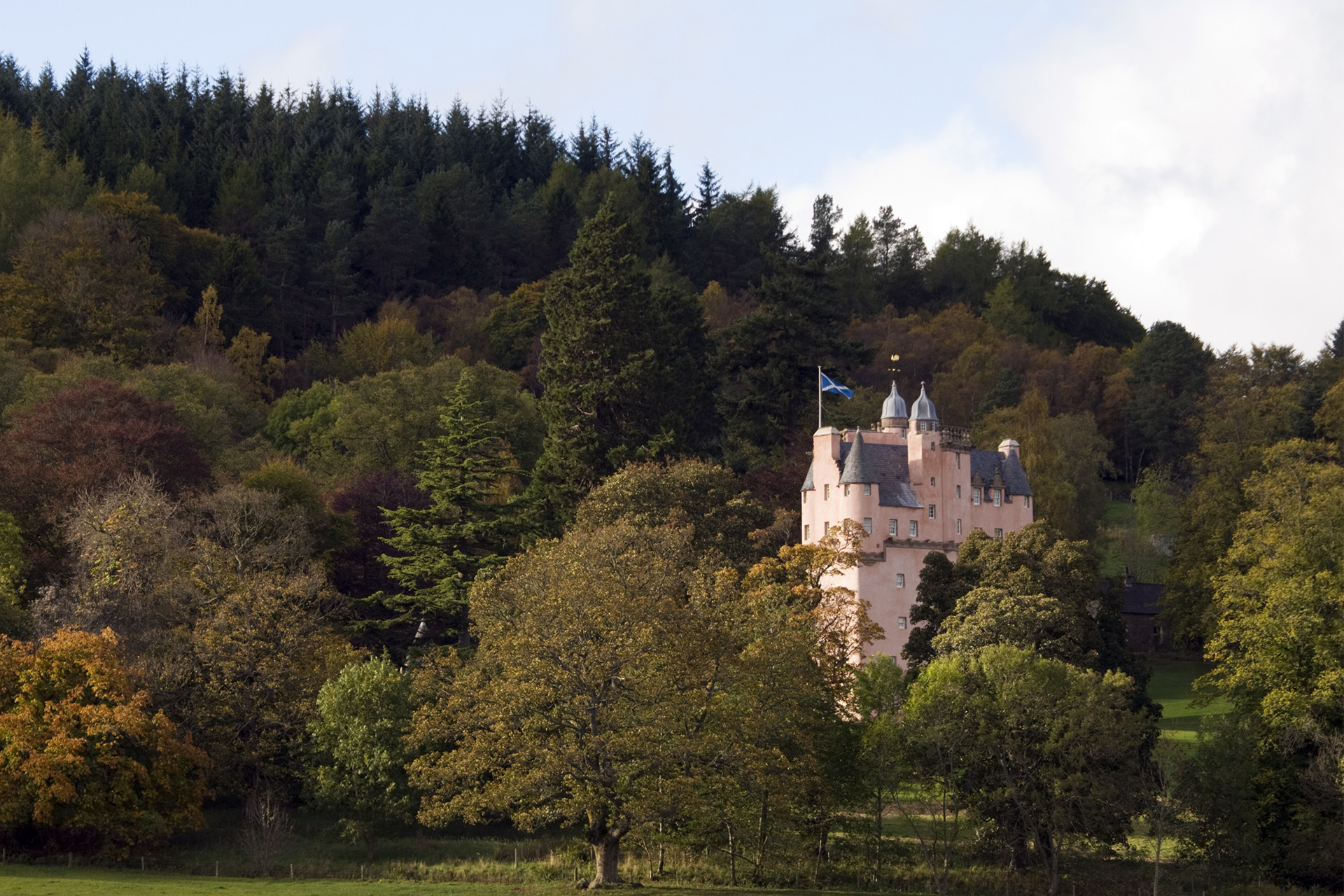 Craigievar Castle in Aberdeenshire, Scotland, surrounded by trees in autumn colours.