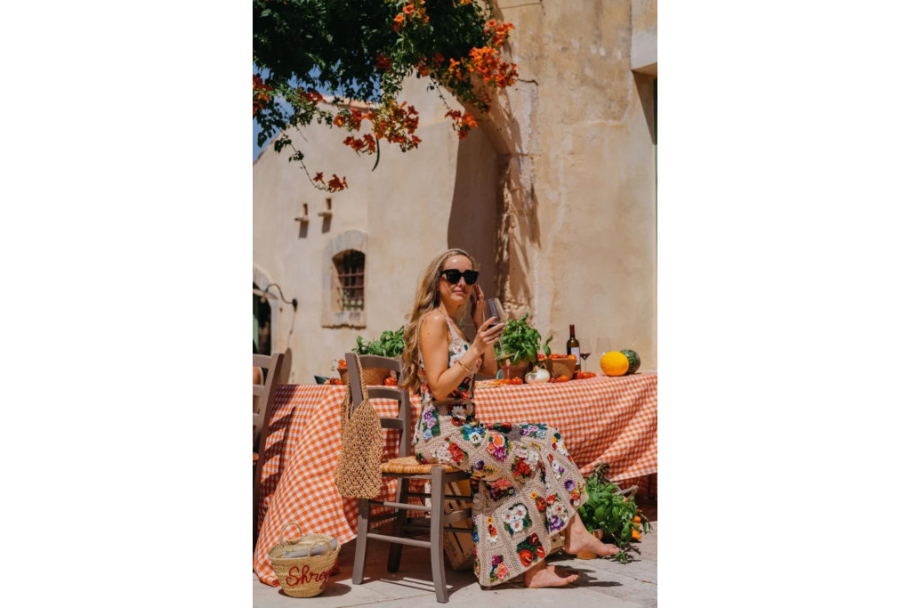 Woman sitting in the sun outdoors by a set table