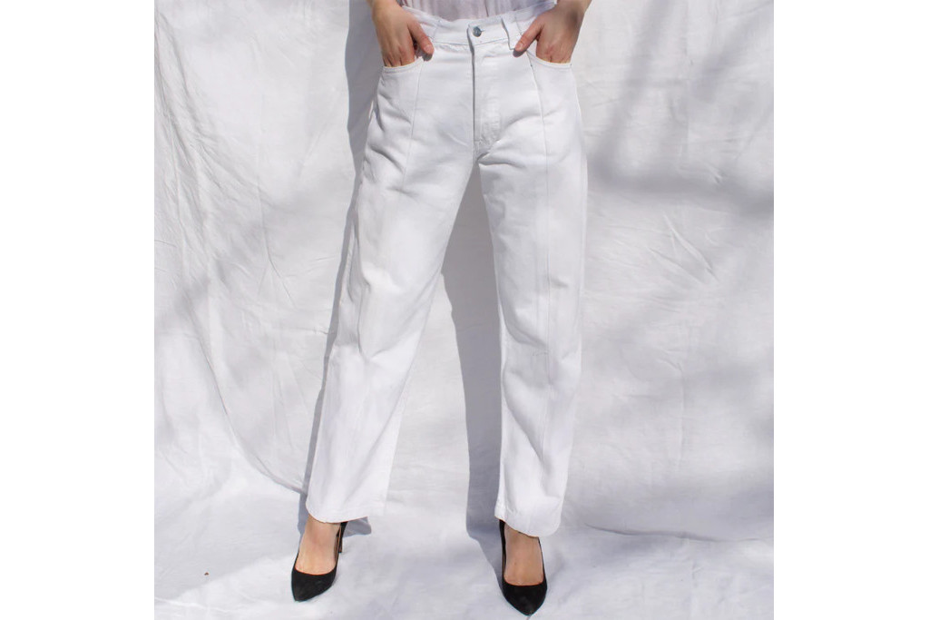 Woman in white trousers and heels stood in front of white shadowy background