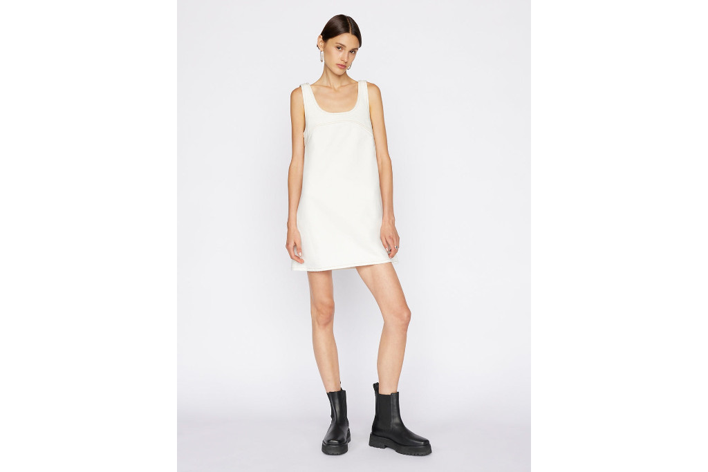 Woman stood in white dress and black boots, stood in front of grey background