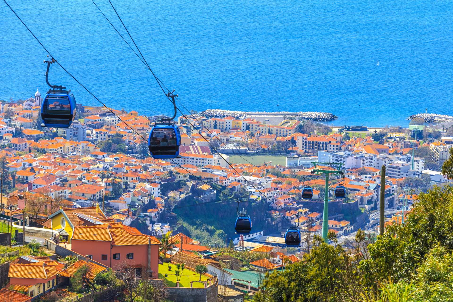 Aerial view of traditional overhead cable cars transporting tourists above Funchal city in Madeira island of Portugal
