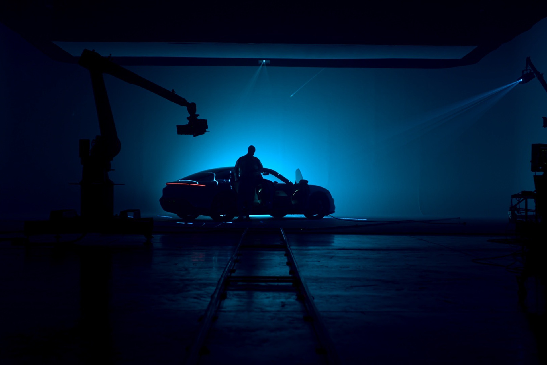 Porsche in dark room with blue backlights, with a man standing next to the car