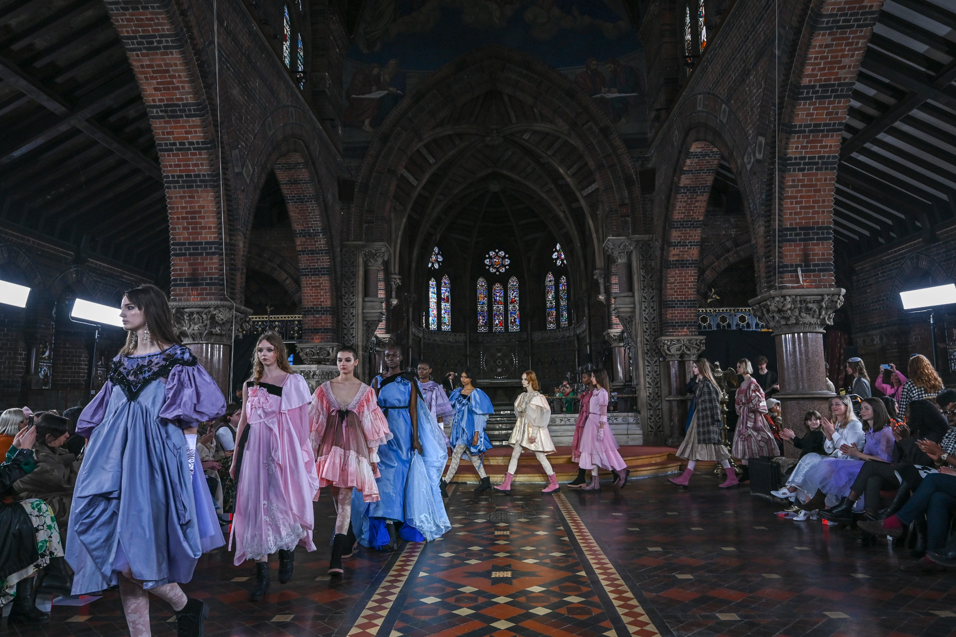 Models in colourful clothing walking through church