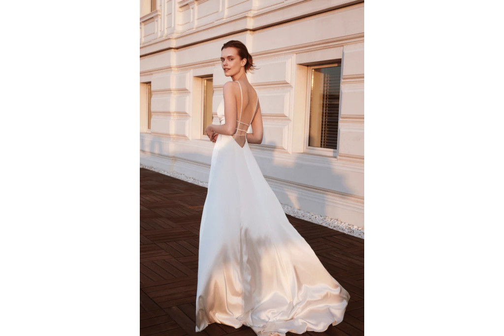 Woman in silky backless white dress walking down the street at sunset