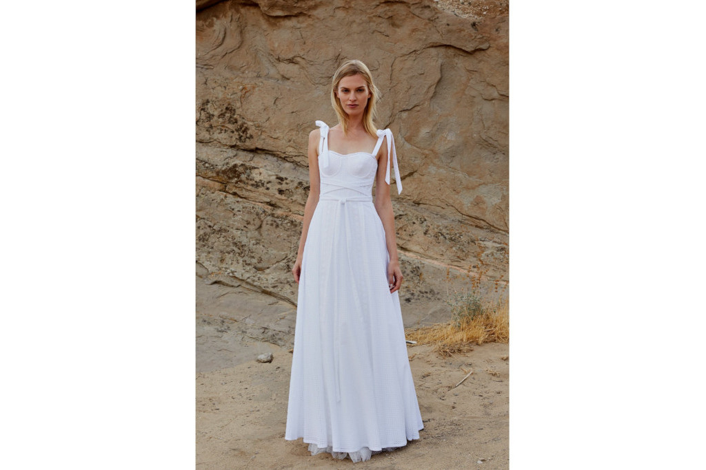 Model on beach waering a white dress