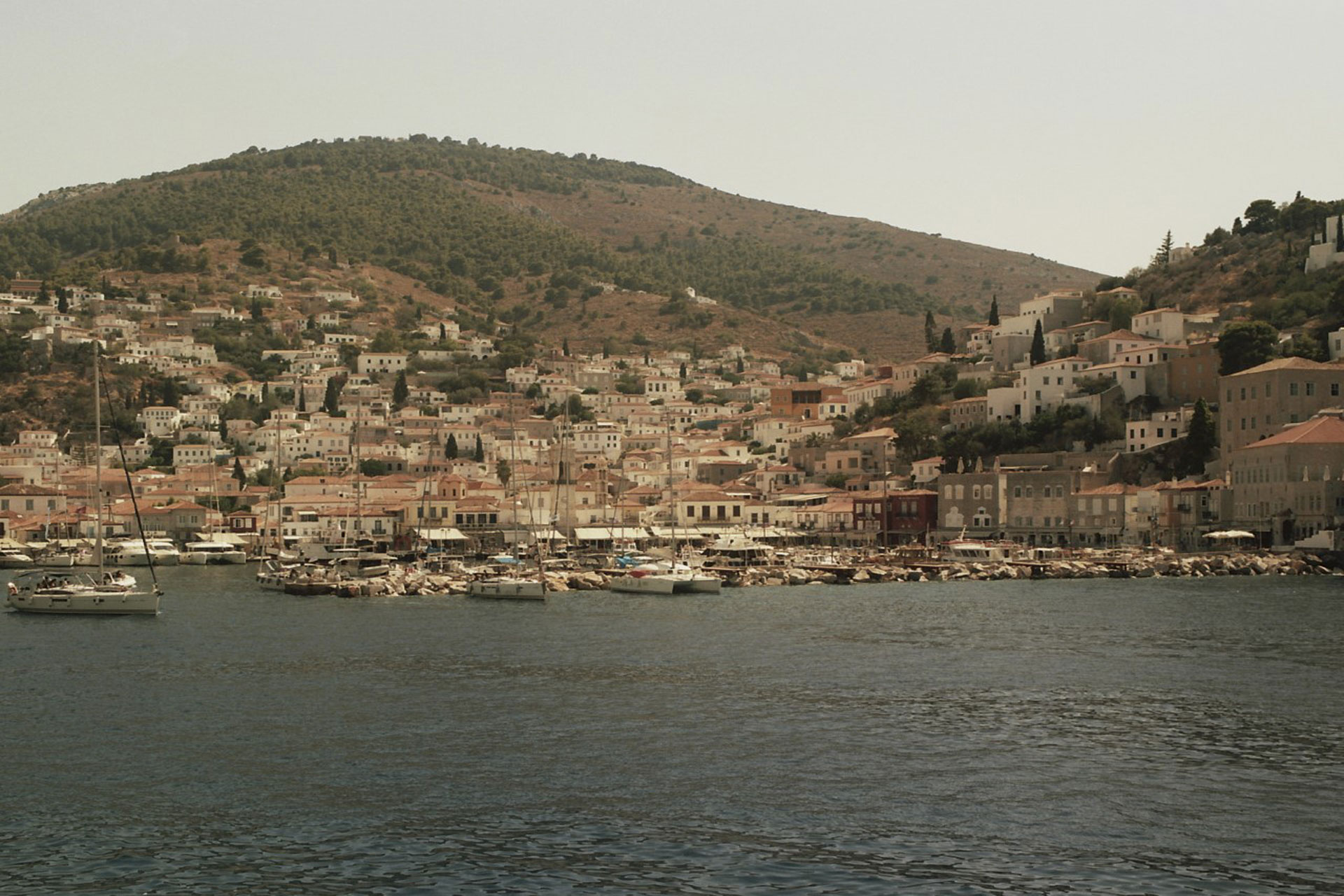 Tall greek hills with white washed houses and ocean ahead of this