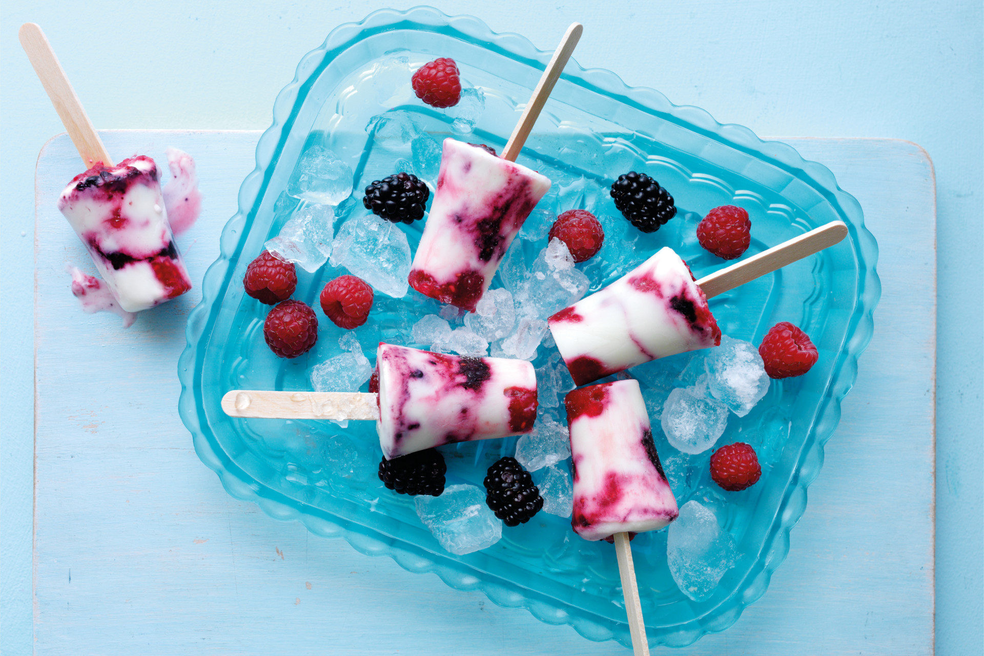 Summer berry swirled lollies in blue dish on light coloured table