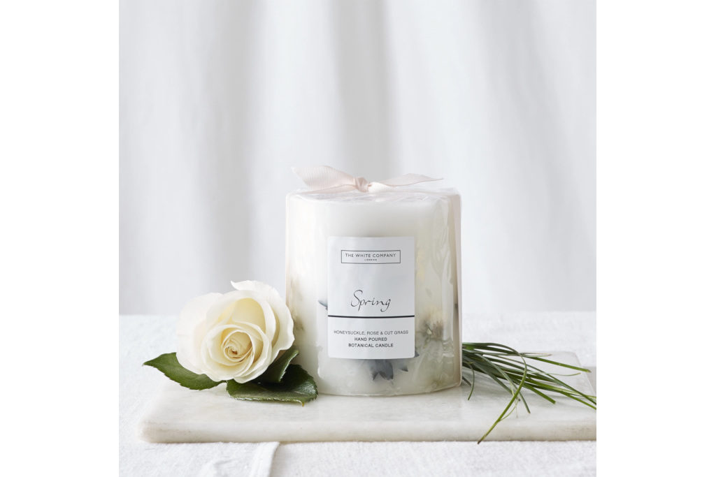 Candle set next to white rose