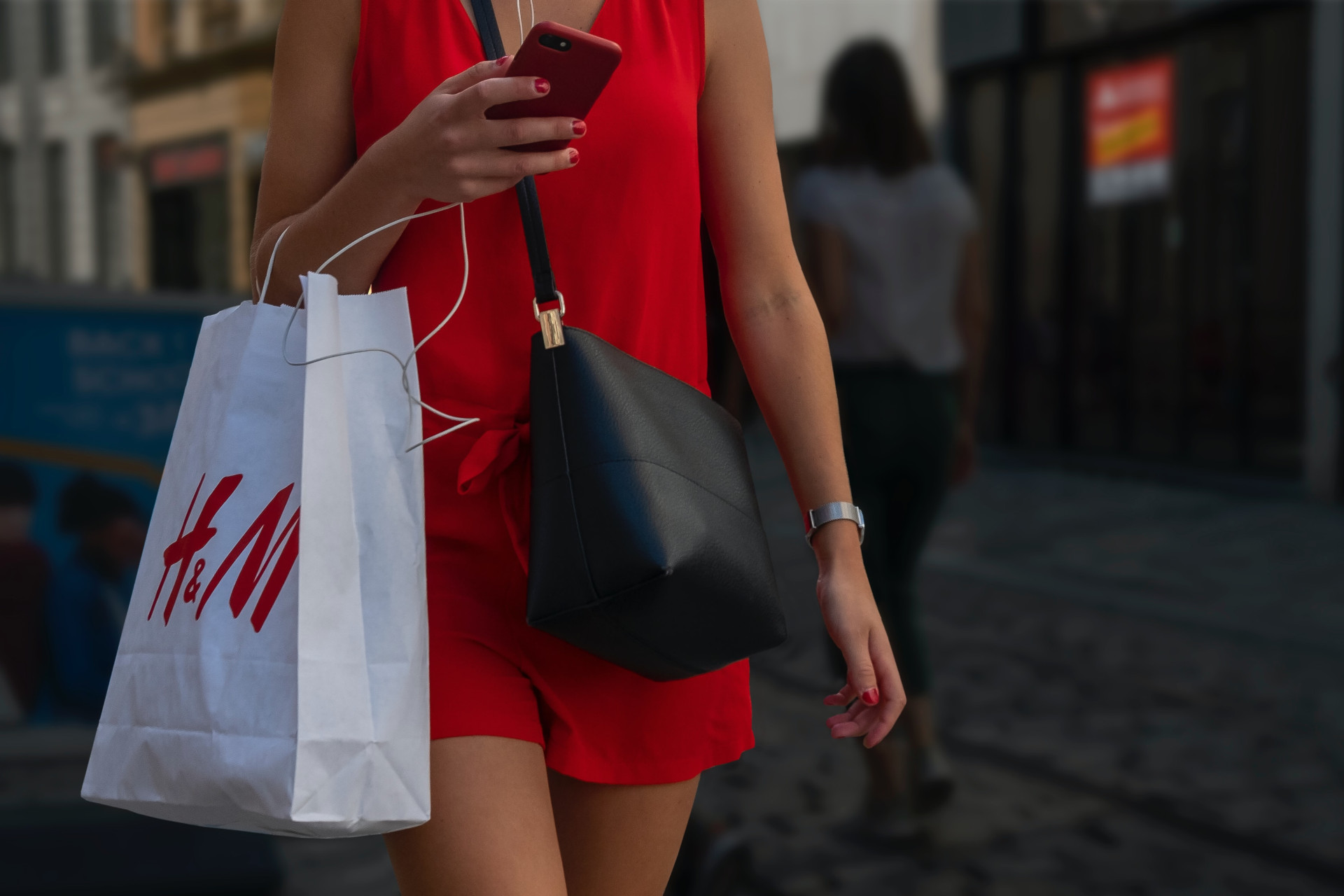 Woman in red dress walking with H&M bag