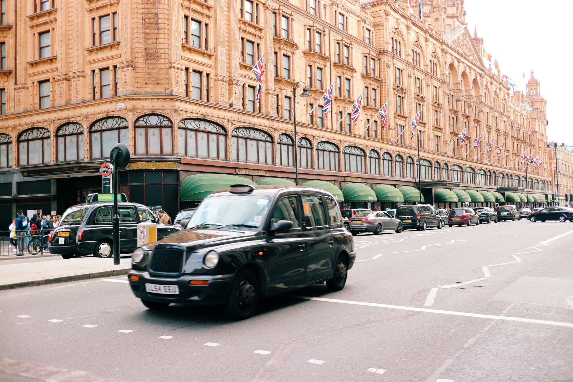 Harrods exterior from street view, with London taxi driving past
