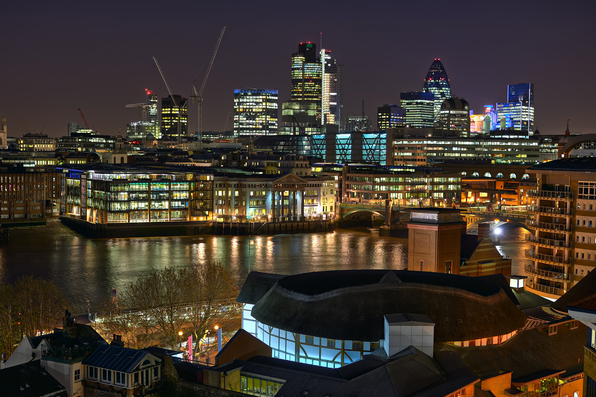 Looking over Shakespeare's Globe Theatre and the River Thames towards the City of London, England, UK, Europe, at night
