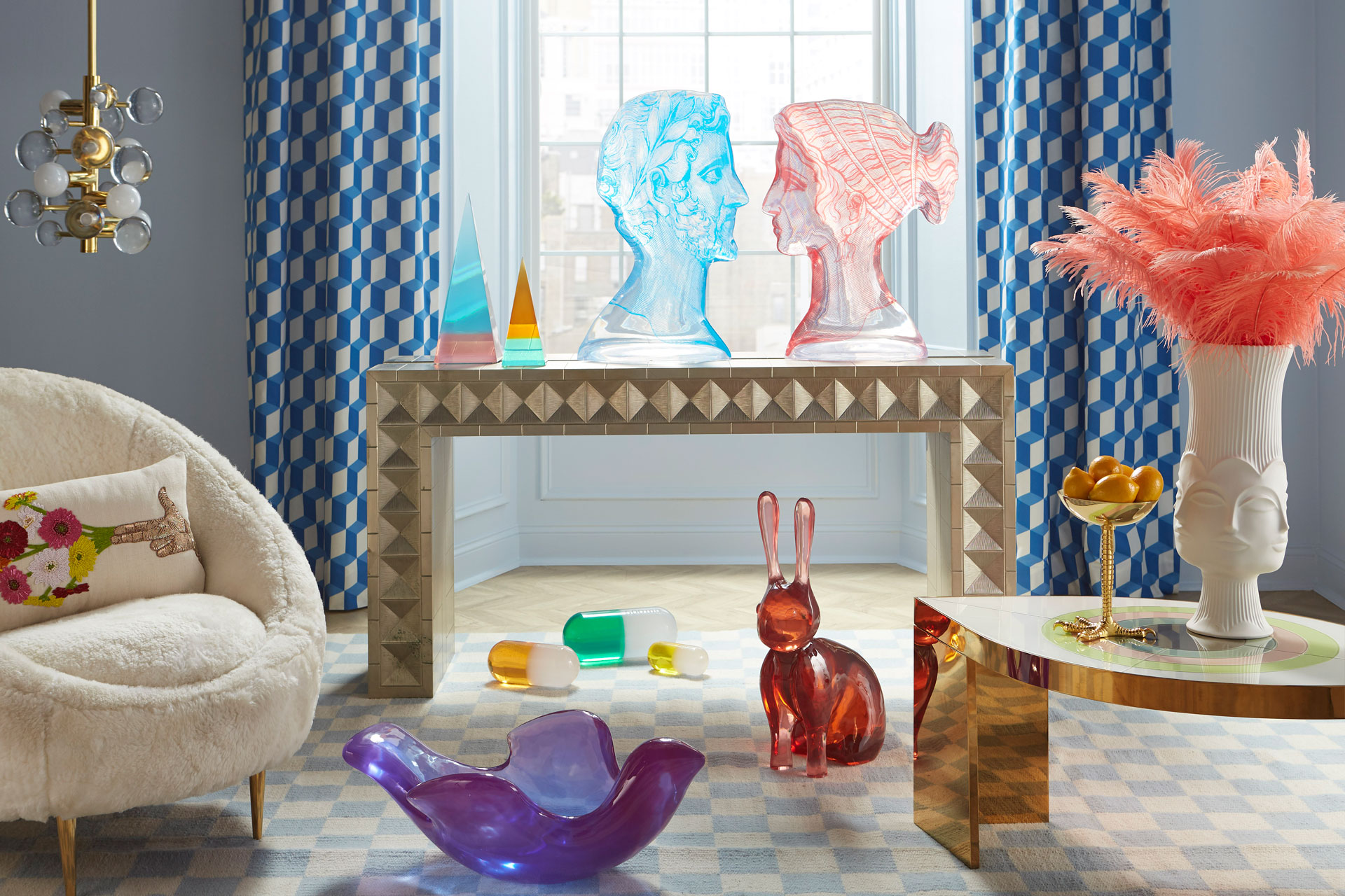 a living room with one blue bust and one red bust, a fluffy arm chair, a purple shell sculpture, a sculpture of a rabbit that is red, and a gold table with pink feathers, on a check carpet, designed by Johnathan Adler