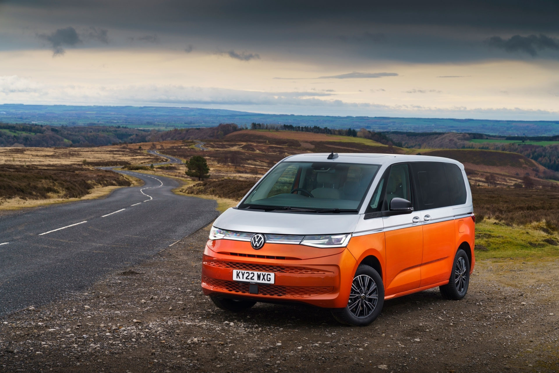 Volkswagen Multivan Life eHybrid is parked on the side of the road in a natural landscape with moody weather