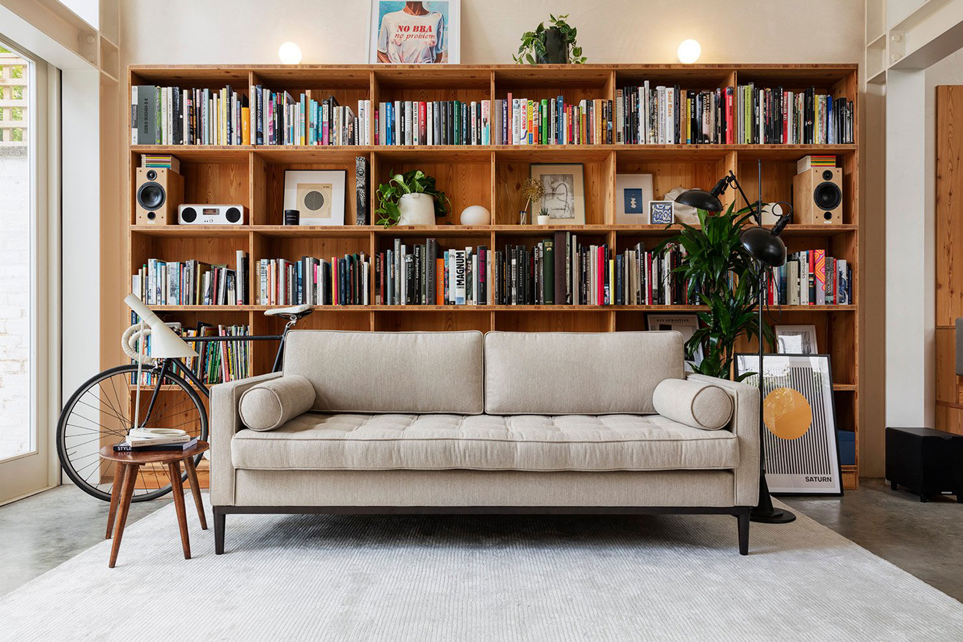 a swyft white statement sofa sits in a living room with a book shelf behind