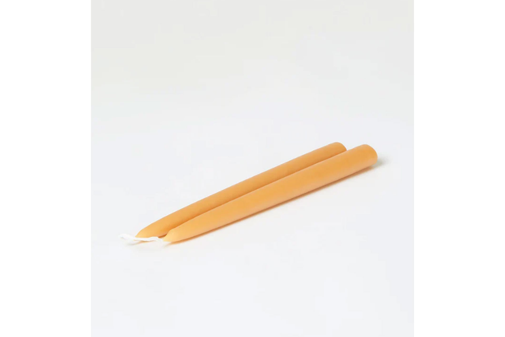 a pair of dinner candles in an orange colour, sold by Toast