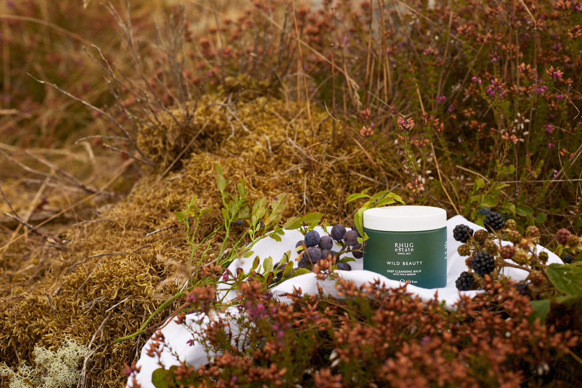 Tub of skincare cream on white sheet nestled in field