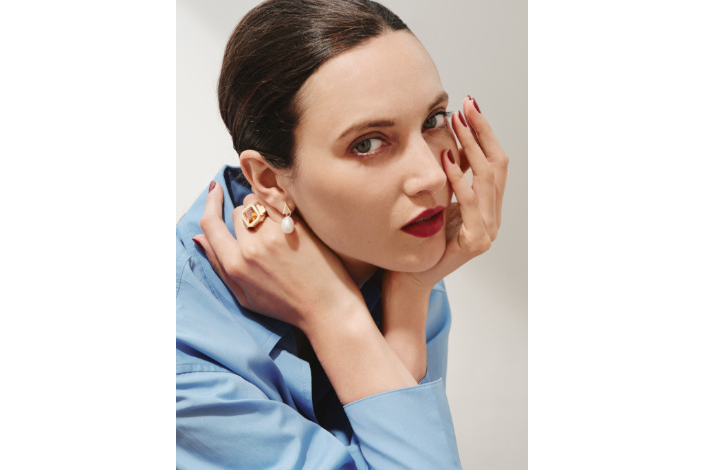 Close up of model's face, with her hands either side decorated in rings
