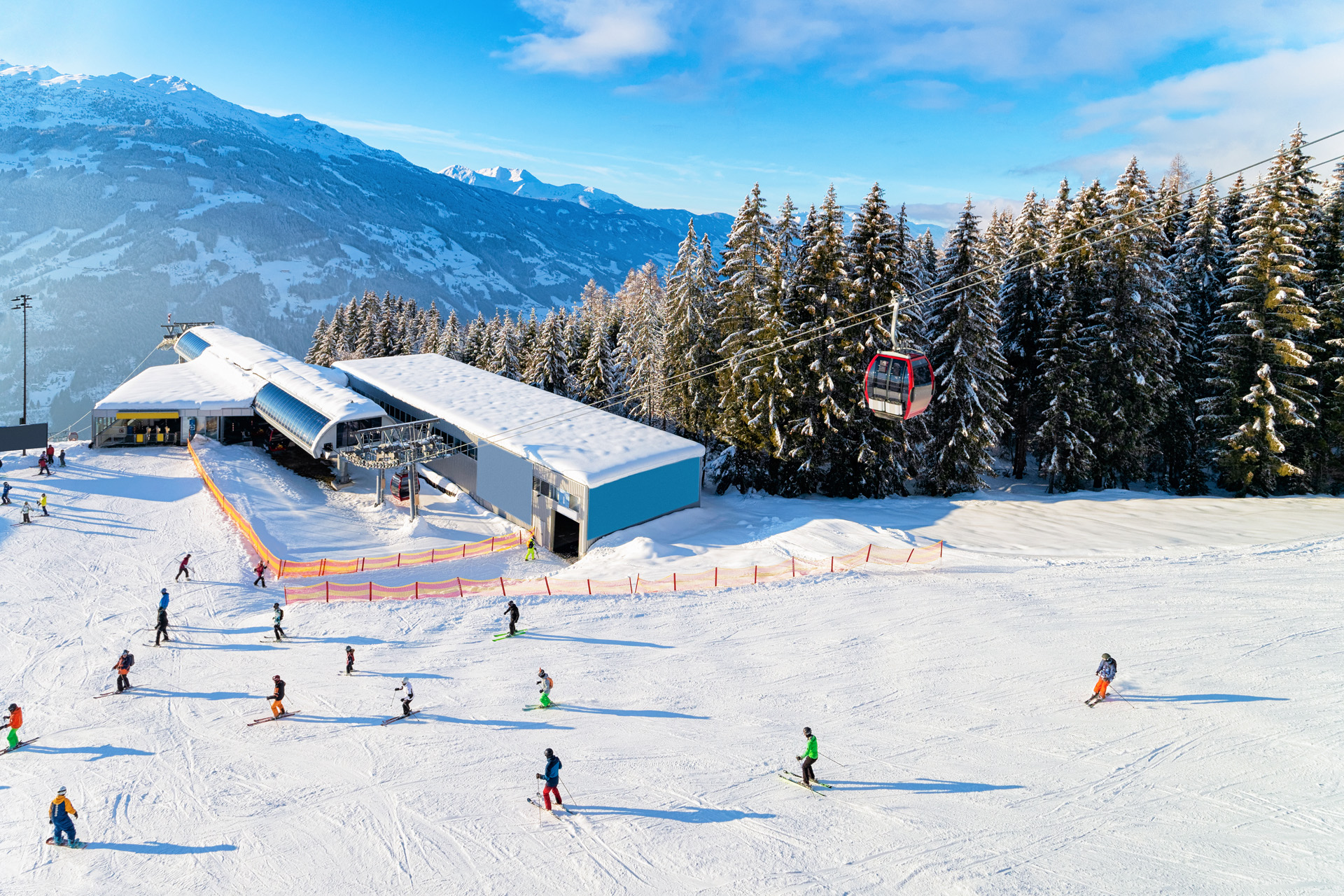 Zillertal ski resort and people skiing and snowboarding in Tyrol in Mayrhofen in Austria in winter Alps. Alpine mountains with white snow and blue sky. Downhill fun at Austrian snowy slopes.