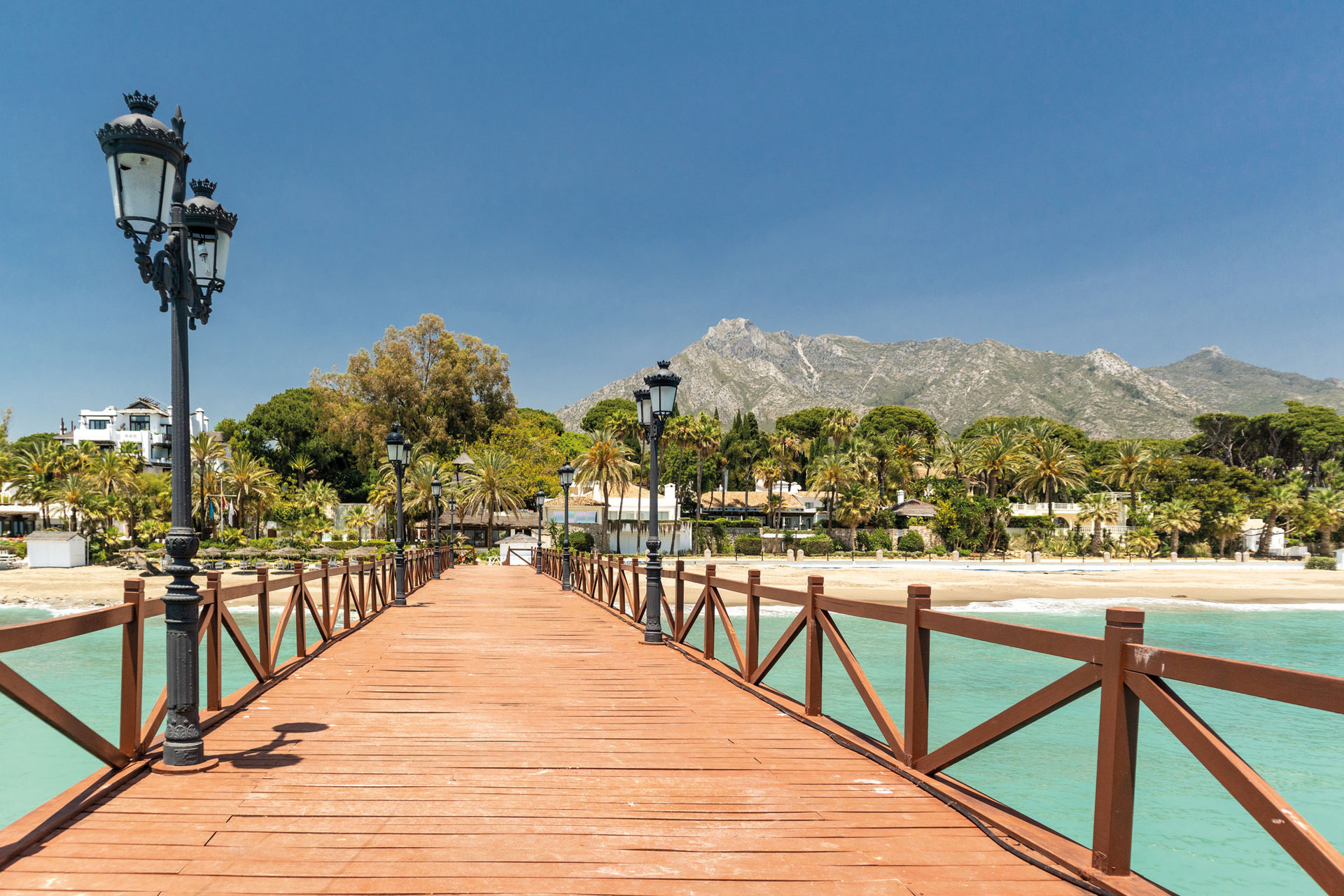 wooden bridge over ocean leading to island 