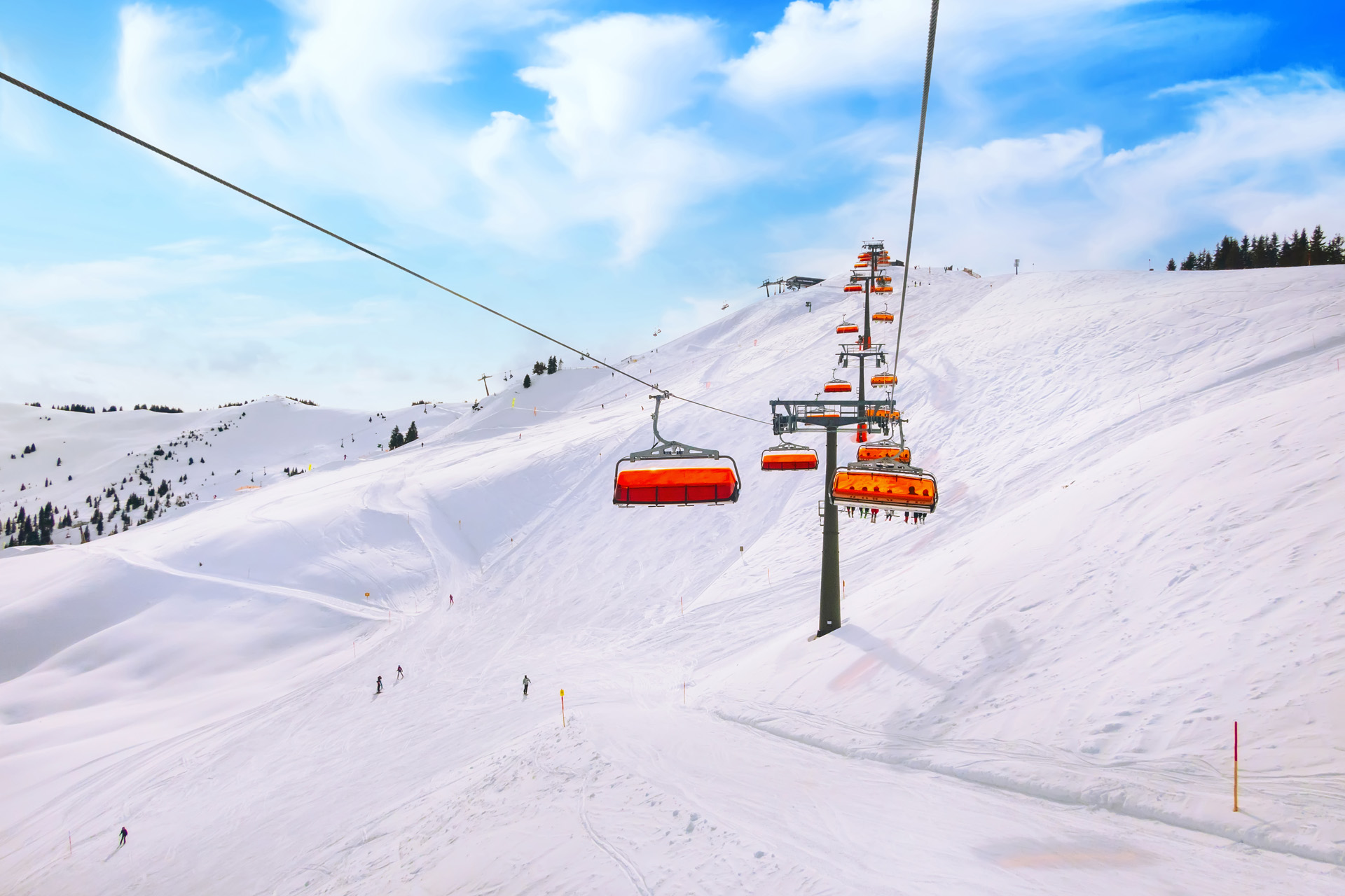 Chair ski lift with orange bubble shelter and ski slope in Saalbach resort, Austria, Alps, Europe.