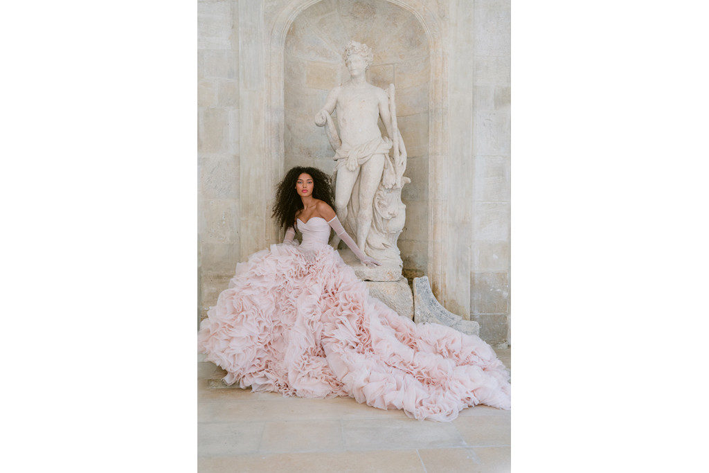 Woman in pink ruffled gown sat by sculpture