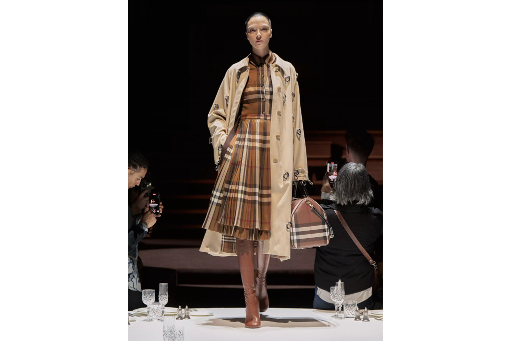Model on the runway in trench coat and pleated check dress